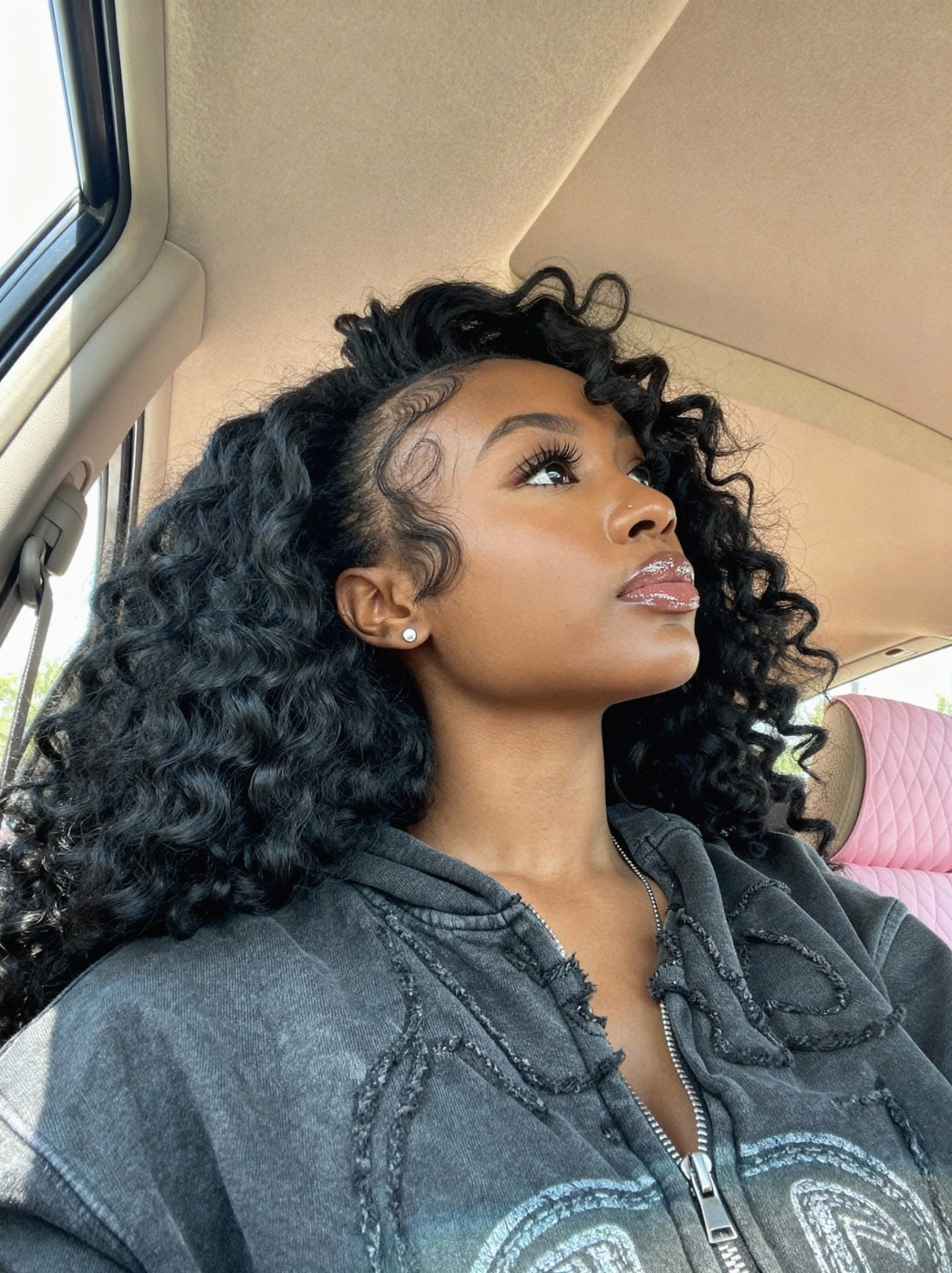 Woman with curly hair sitting inside a vehicle wearing raw cambodian curly hair