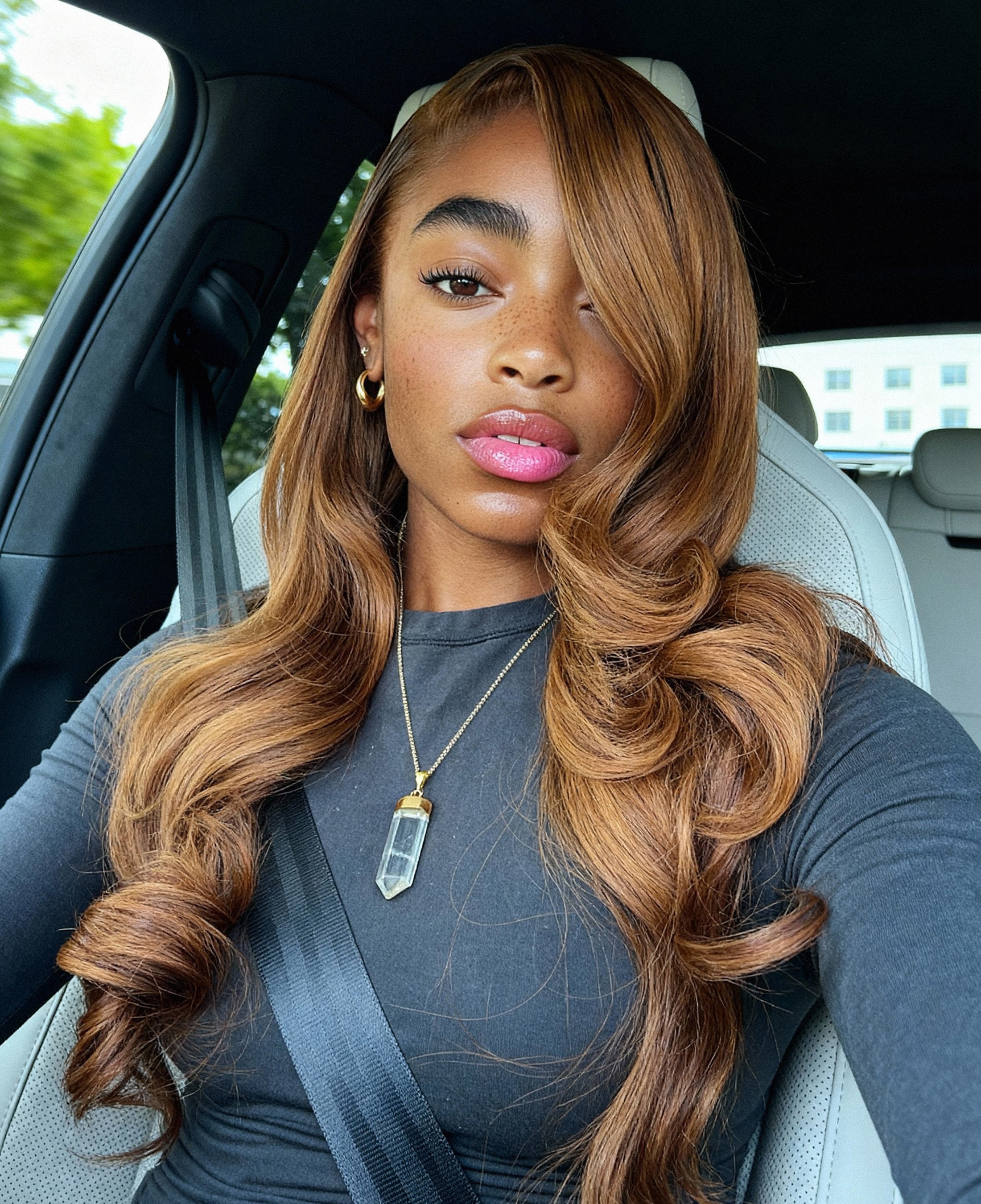 Woman with long, wavy hair sitting in a car, raw indian hair